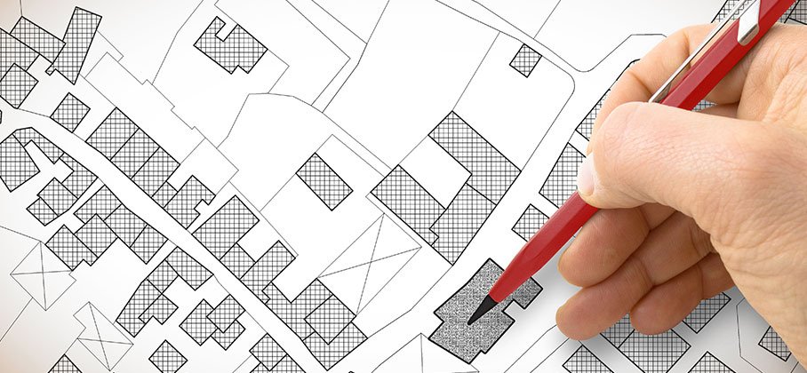 Person with pen pointing to a zoning property map